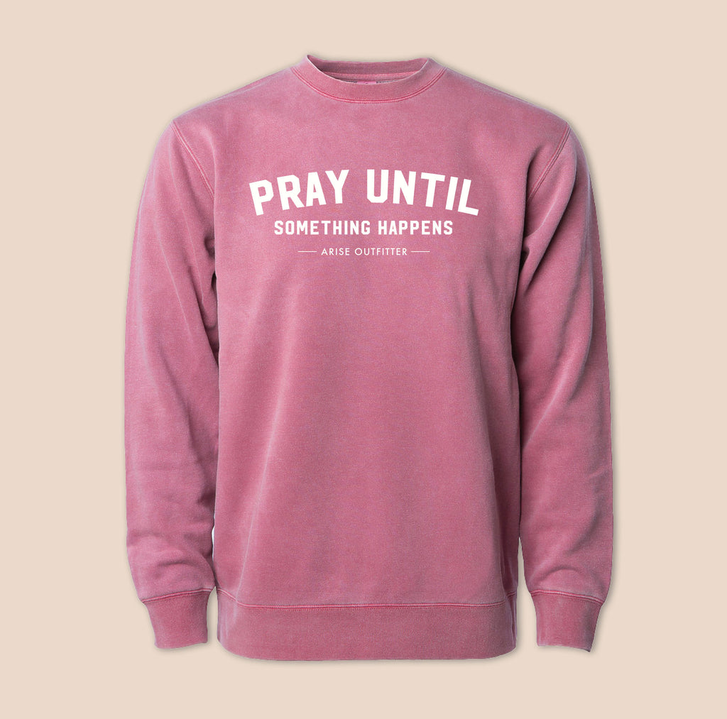 Pink crewneck sweatshirt with 'PRAY UNTIL SOMETHING HAPPENS' text on a beige background Maroon Color.