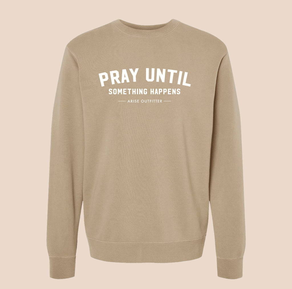 Beige sweatshirt with text 'PRAY UNTIL SOMETHING HAPPENS' on a beige background